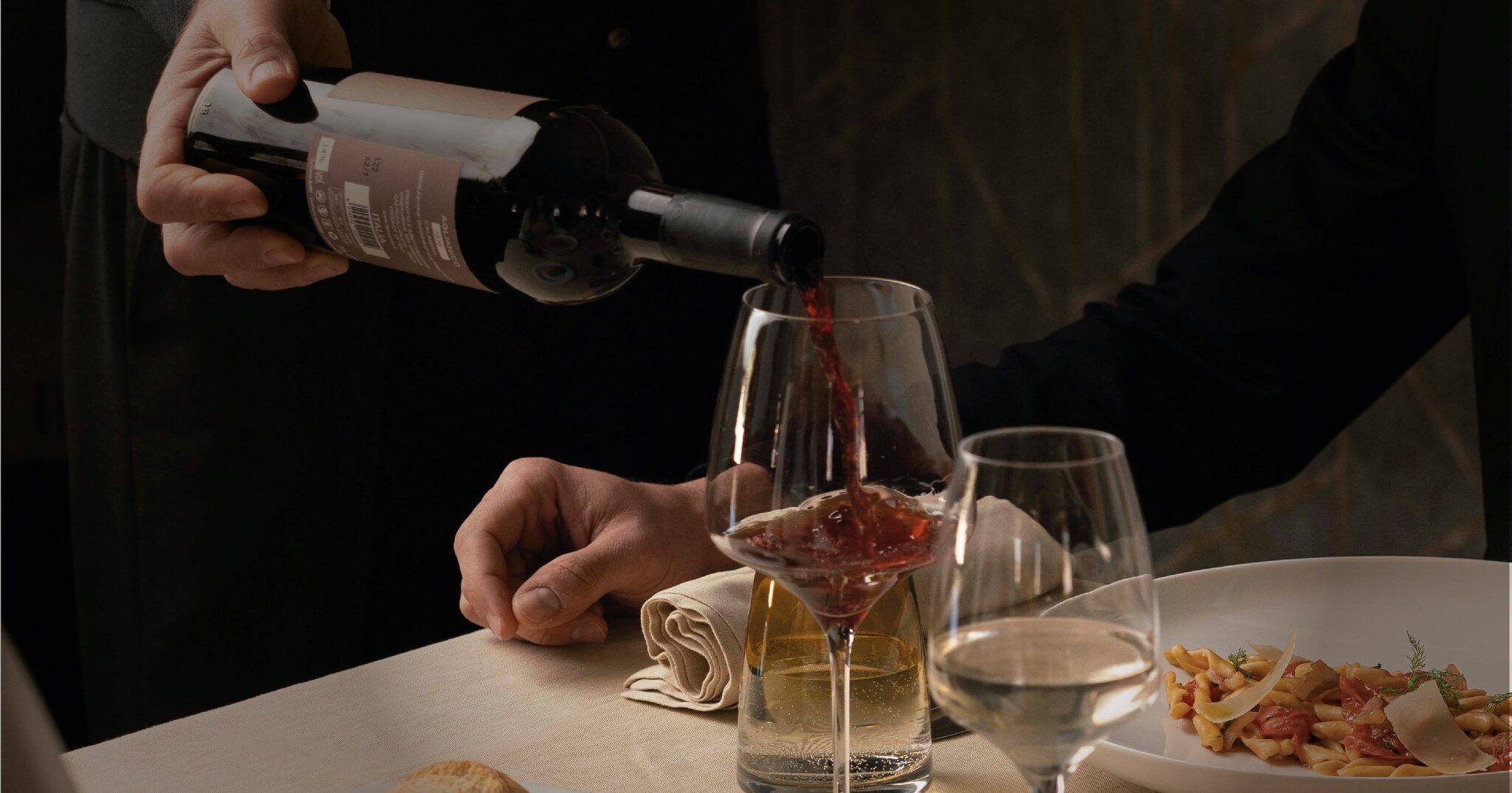Particolare di un cameriere versa del vino durante una romantica cena di ospiti in pineo relax